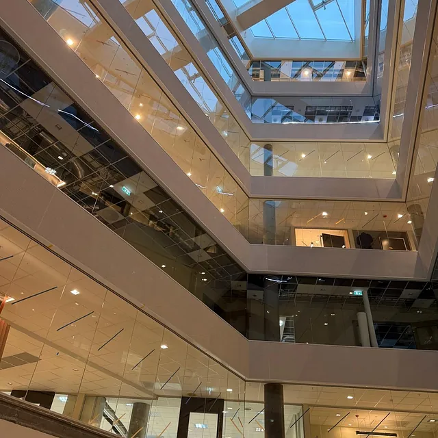 Fleretasjes bygg med glassvegger og lyst atrium.