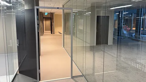 Glasskontorer med dør og gang i kontorbygg.